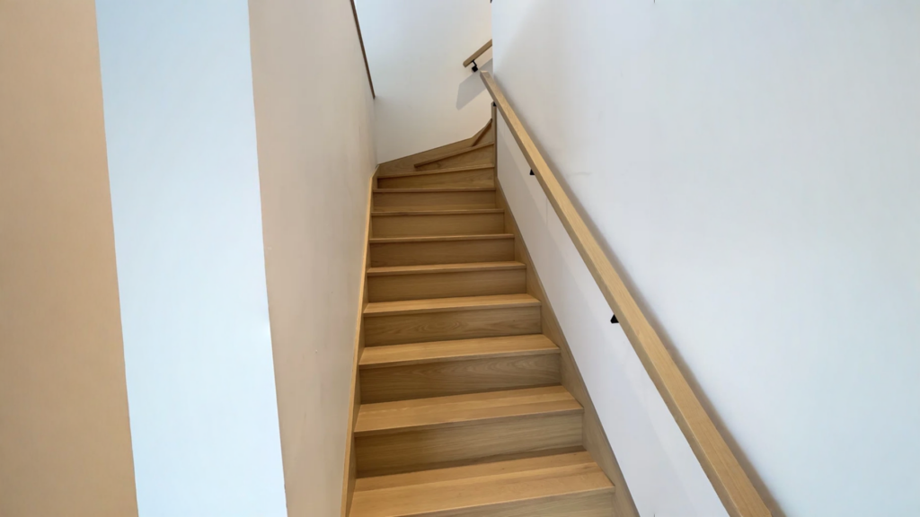 Escalier tournant en chêne blanc entre deux murs à marches rayonnantes