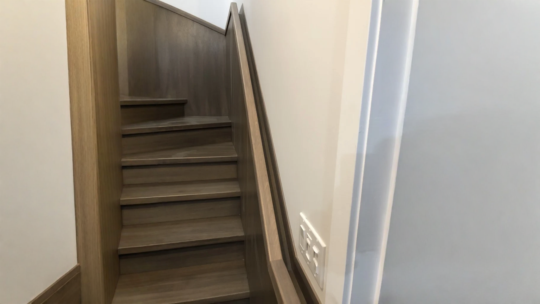 Escalier tournant en bois gris-brun à limons fermés et main courante murale — vue principale