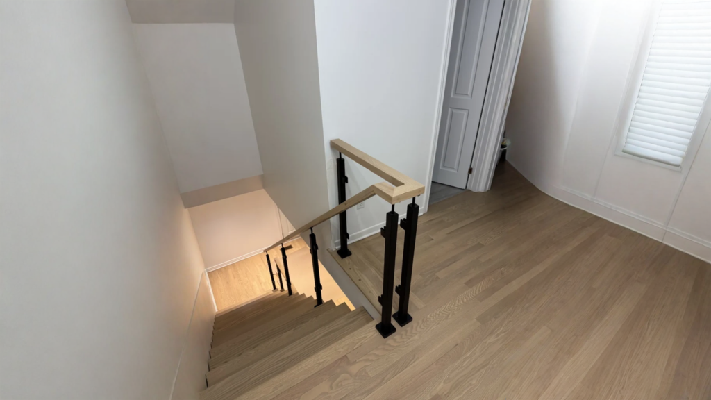 Escalier tournant en chêne blond, poteaux noirs et main courante bois