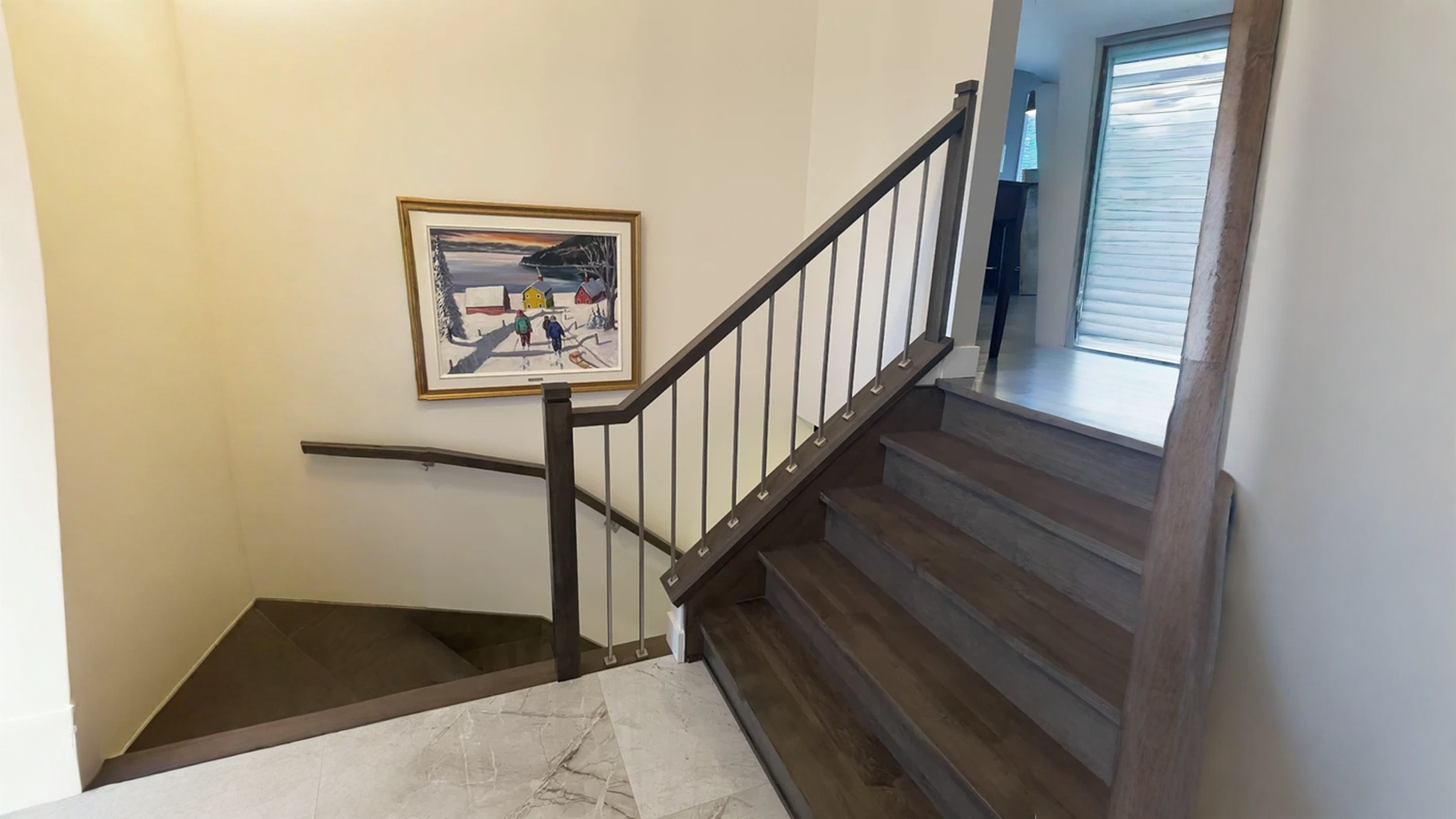 Escalier tournant en bois teinté foncé à barreaux métalliques dans un hall — vue principale