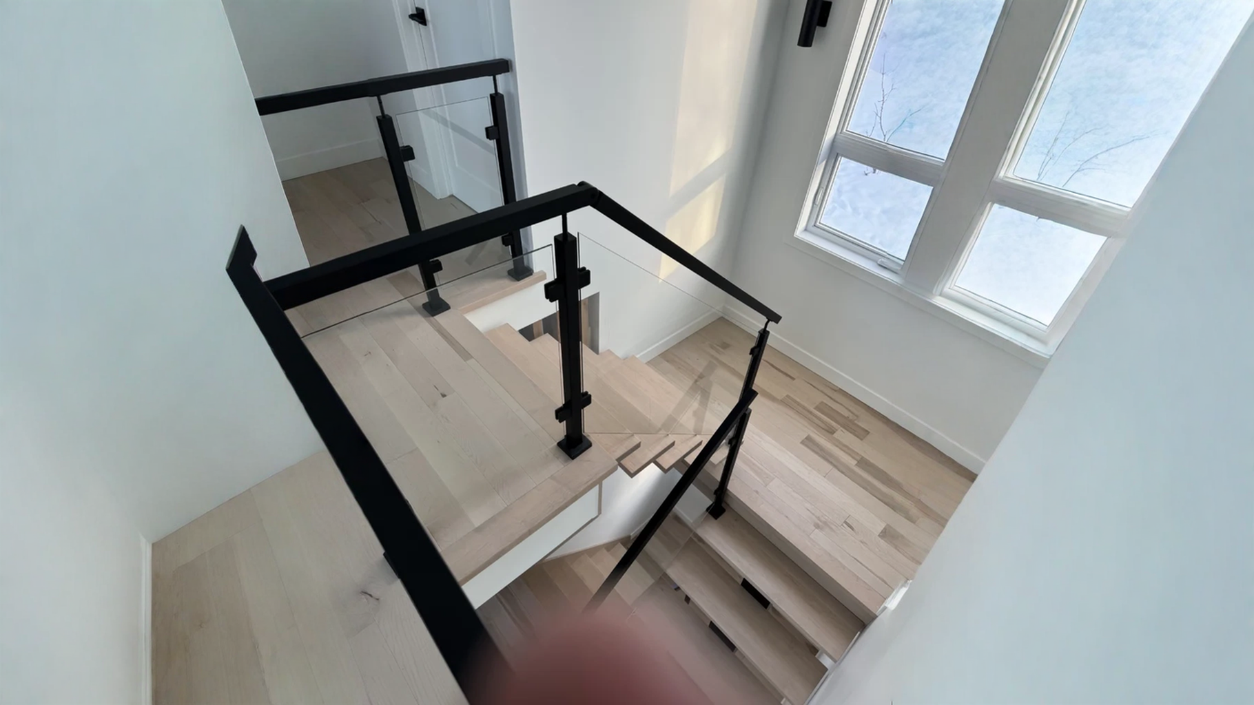 Escalier tournant à garde-corps de verre et poteaux métalliques noirs — vue principale