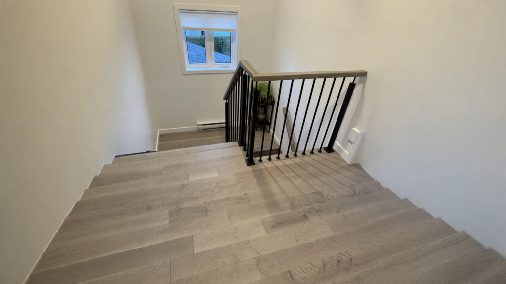 Escalier tournant en érable teinté gris à barreaux d’acier noir
