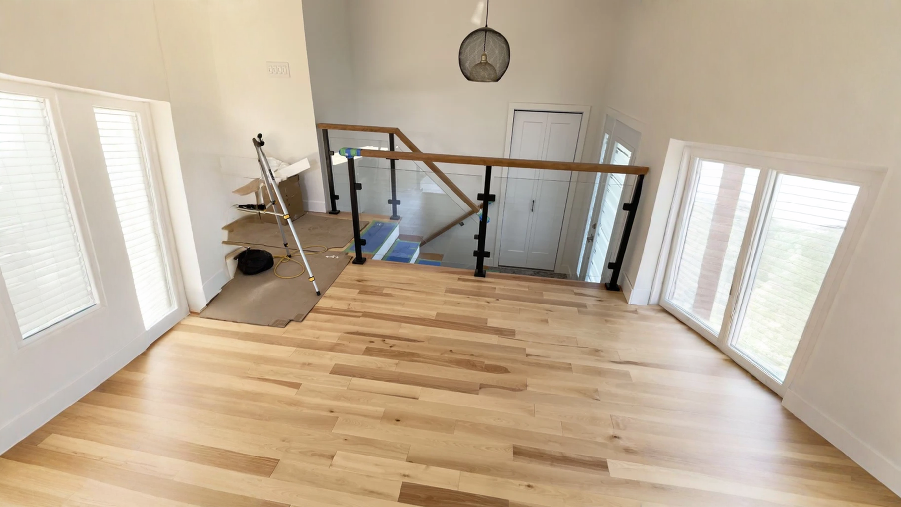 Trémie d’escalier bordée d’un garde-corps de verre et d’une main courante de bois — vue principale
