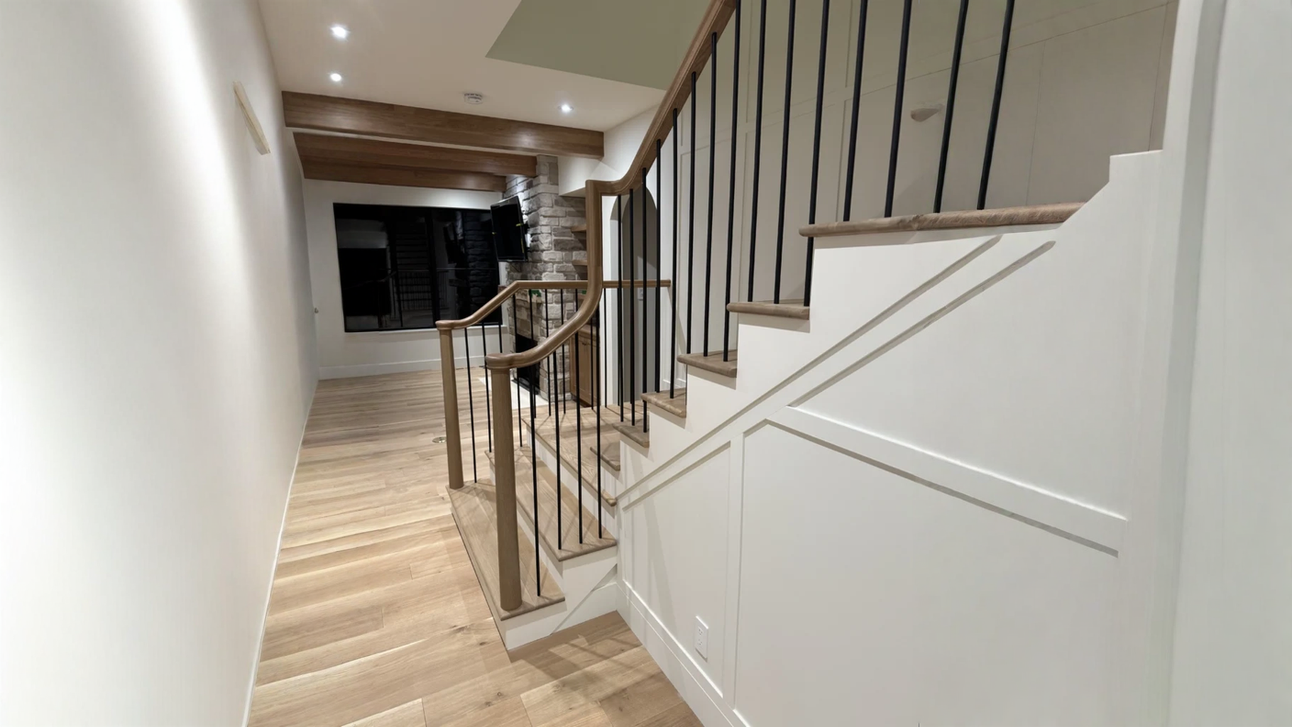 Escalier tournant à barreaux d’acier noir et boiserie sur mur de pierre — vue principale