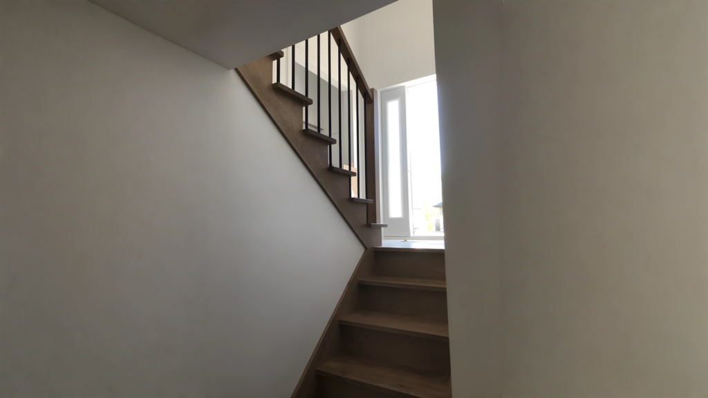Escalier tournant en bois franc teinté gris-brun à barreaux métalliques noirs