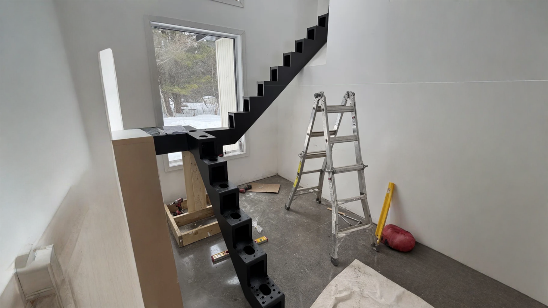 Escalier à limon central d’acier noir en cours d’installation — vue principale