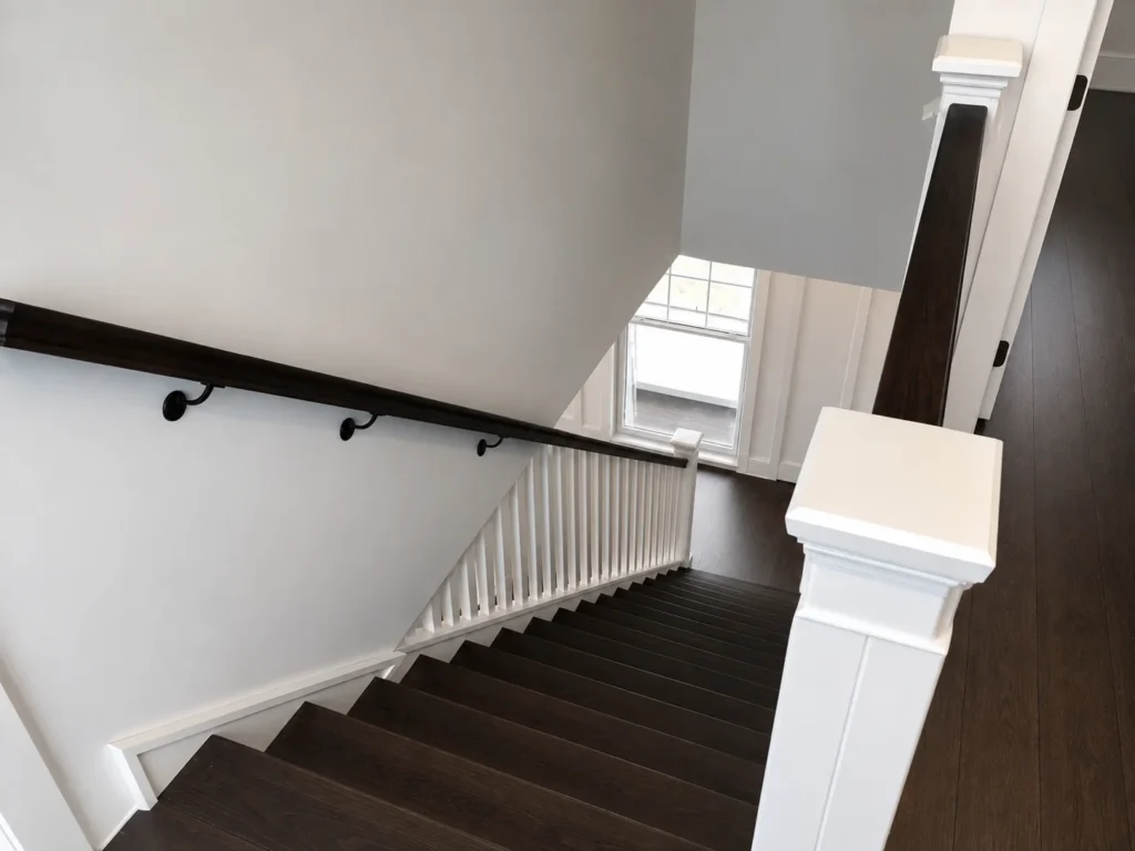 Escalier tournant deux tons avec barreaux de bois blancs et main courante foncée