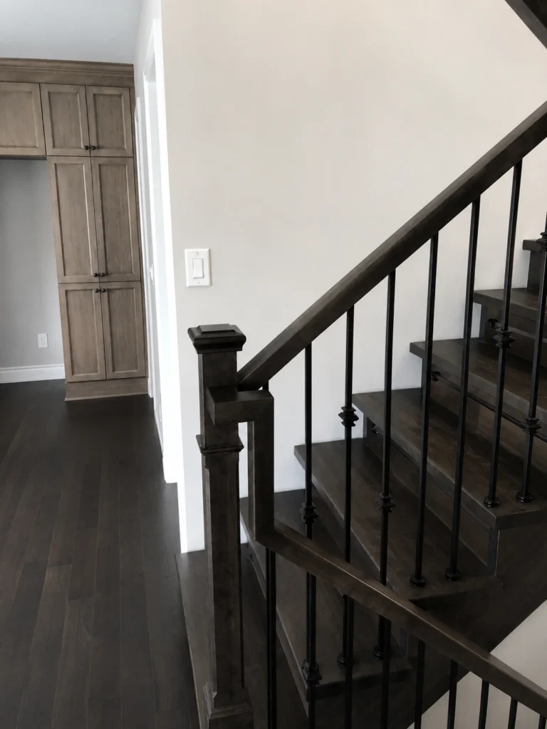 Escalier tournant en bois teinté gris-brun à barreaux d&rsquo;acier